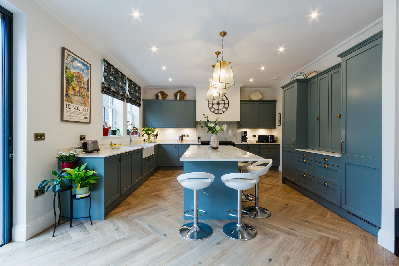 A bright, renovated shaker kitchen with a central island, pendant lighting and herringbone floor